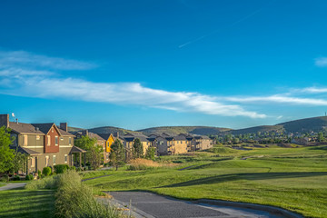 Houses around a golf course with scenic background of mountain and blue sky