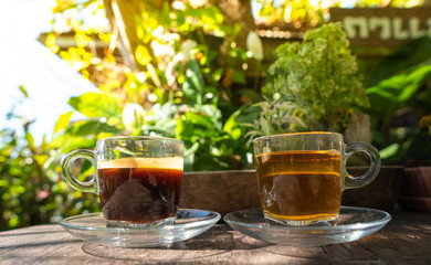 Hot tea and hot coffee cup top on wooden with coffee shop in the garden.