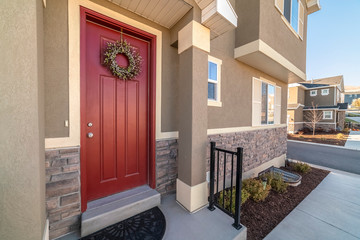 Colourful red entrance door with wreath near sunset