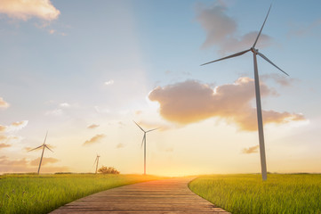 Green energy concept. Wind turbines and wooden bridges with green field and sunset backgrounds.