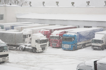 Trucks loading at warehouse and transport terminal. Parking in severe winter weather storm....