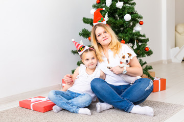 Happy mother with her daughter and jack russell terrier dog sitting near the Christmas tree
