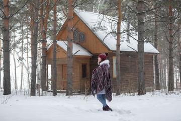 Portrait of a girl in a warm gray coat and burgundy knit scarf in the winter woods.