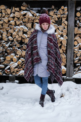 Portrait of a girl in a warm gray coat and burgundy knit scarf in the winter woods.