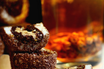delicious sweets with nut filling in chocolate crumbs on the background of a glass of tea