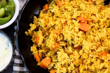 ndian Vegetable Pulav or Biryani made using Rice and vegetables like peas, carrots, beans. served with raita and saute peas, capsicum bowl.