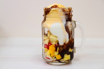 Mango & vanilla ice cream served with Mixed chopped fruits like Bananas, Mangoes, pomegranates, apples garnished with chocolate syrup in a glass. known as Gad bad ice cream in India © Manaswi