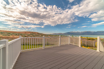 Back porch of a home with view of lake and mountain under cloudy blue sky