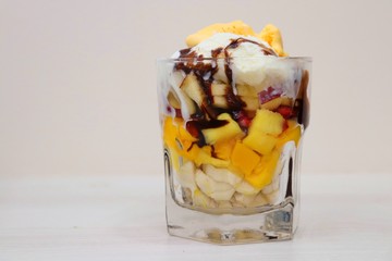 Mango & vanilla ice cream served with Mixed chopped fruits like Bananas, Mangoes, pomegranates, apples garnished with chocolate syrup in a glass. known as Gad bad ice cream in India © Manaswi