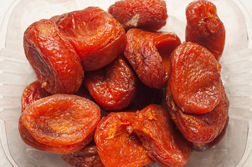 Dried apricots in a plastic container. The norm of dried fruits for an adult.