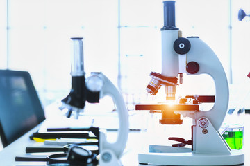 Microscope and test tubes with lab glassware in laboratory background, research and Scientific...