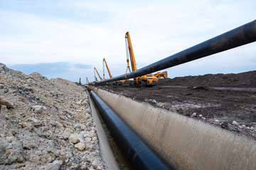 Gas pipeline construction. Heavy duty construction machines placing gas pipe into the ground.