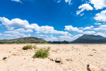 dry sand ground of Mae Khong river with Mountain views on blue sky background texture with white cloud of Laos at the Kaeng Khud Khu rapids at Chiang Khan in Loei province,Thailand,The River Crisis