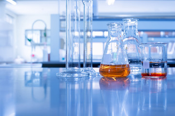 glass flask beaker and cylinder in chemistry blue laboratory background
