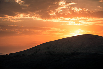 Obraz premium The sun rising at dawn over the hills of the Hluhluwe - imfolozi National Park in South Africa