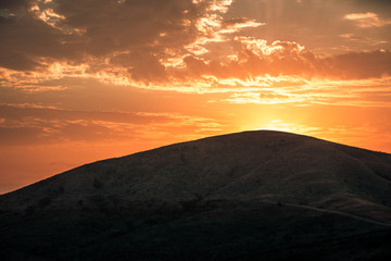 Obraz premium The sun rising at dawn over the hills of the Hluhluwe - imfolozi National Park in South Africa