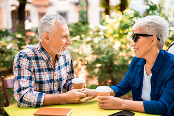 Beautiful senior couple holding hands in outdoor cafe