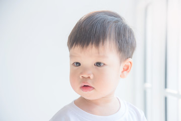 Closeup face of Little asian boy looking at something in the house.