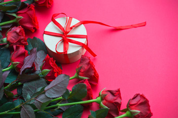 Bouquet of red roses and a craft box with a red ribbon on wooden background. Birthday. Valentine's day. March 8. Mother's day. Greeting card. Wallpaper