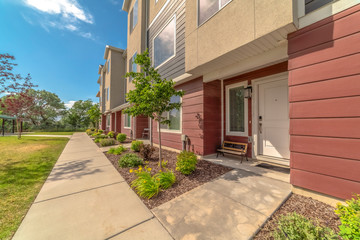 Sunny day view of townhomes with pathways on the yard leading to front doors