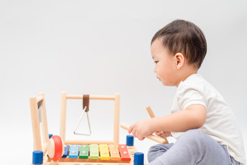 Little baby drummer boy playing percussion and hitting the drum set at home.Asian boy playing and...