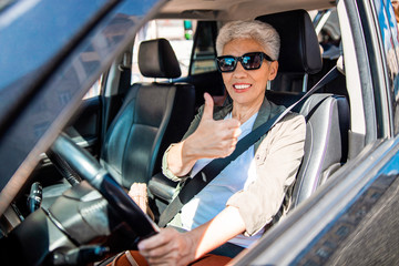 Obraz premium Cheerful elderly lady in auto doing thumbs up