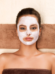 Young woman with mask on her face relaxing in the spa salon.