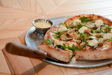Delicious Italian large pizza served on a light wooden table in a restaurant. Restaurant food photography
