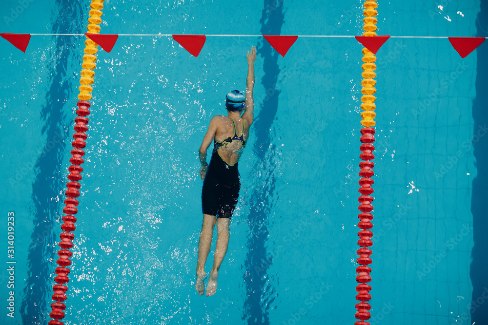 Wall mural Young woman swimmer swims in swimming pool