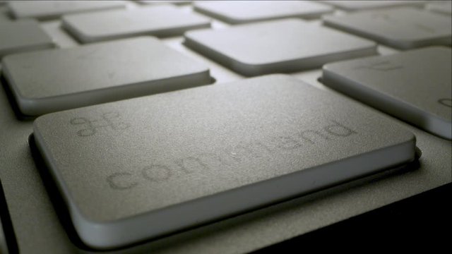 Close up of keyboard as finger presses the command key moving across in low angle view.