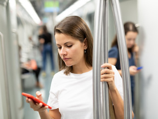 Girl using phone in underground carriage