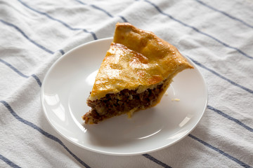 Slice of Homemade Canadian Tourtiere Meat Pie on a white plate , low angle view. Close-up.