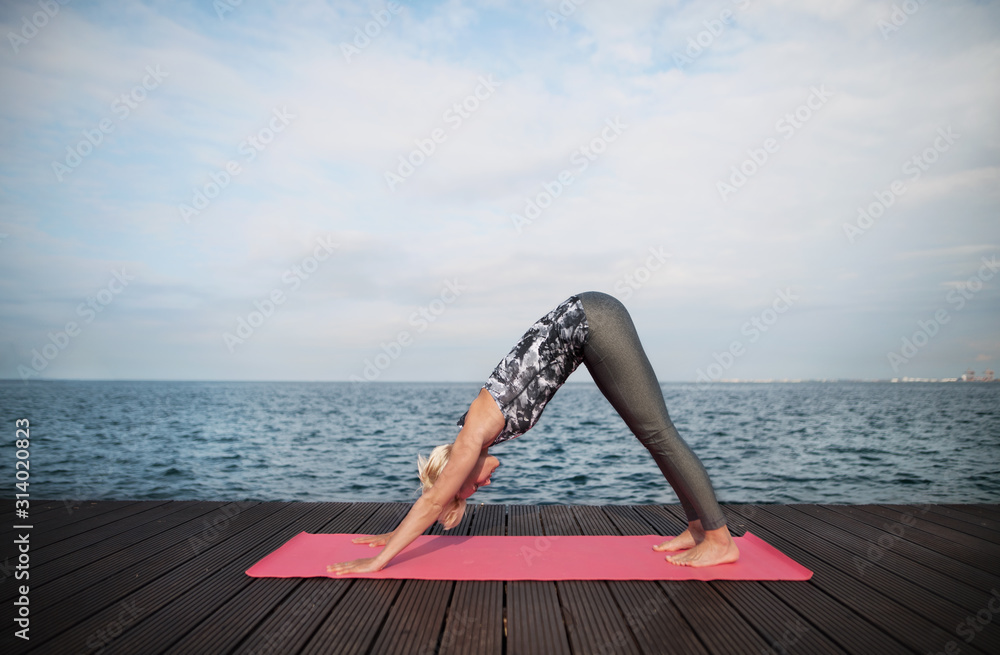 Wall mural a portrait of young sportswoman doing exercise on beach. copy space.