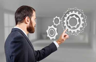 Businessman touches virtual gears cooperation.