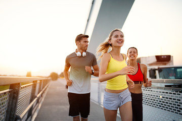 Fit happy friends jogging and running together outdoor in city