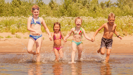 group of beautiful children runs in a wig and splashes water on a summer hot sunny day