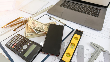 Computers and phones and dollar calculators. Ruler and documents on the table.