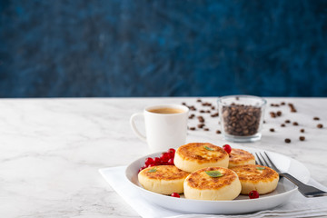 Syrniki or cottage cheese pancakes with fresh red currant, and cup of black coffee. Tasty healthy breakfast. Copy space.