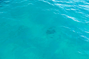 Clear water texture in blue. Background of the ocean and the sea backlit by the sun.