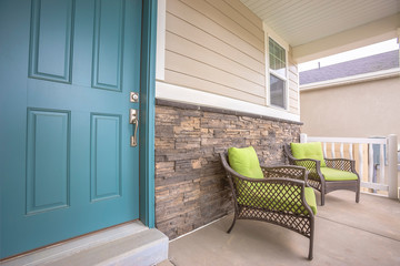 Porch armchairs against brick wall of a home with blue front door