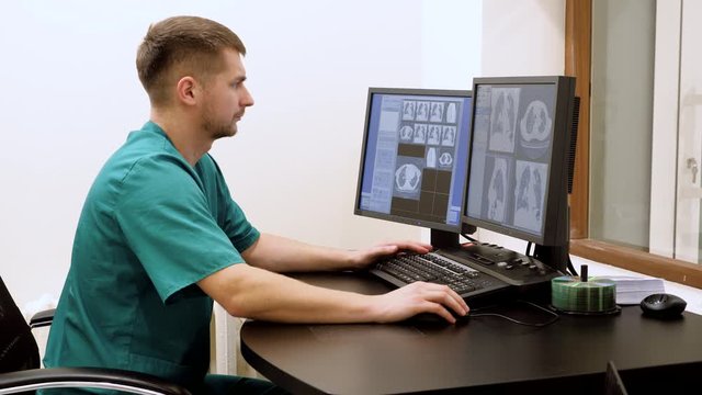 Medical professional doctor looking at patient scans on computer screens in modern clinic. 4K