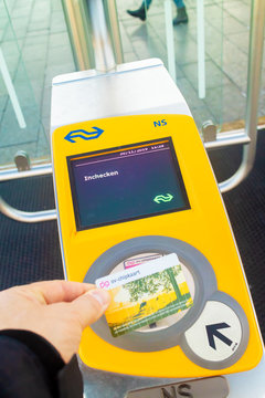 Commuter holding railway card in front of a train automated check-in on a Dutch railway station in Apeldoorn, The Netherlands on November 30, 2019