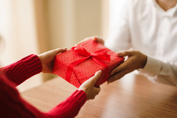 Valentine's Day, holiday and surprise concept. Man gives to his woman a red gift box. A loving...