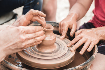 A close up view on ceramic production process on potter's wheel with children. Clay crafts with kids concept.