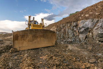 Excavator pushing rock in an open pit mine