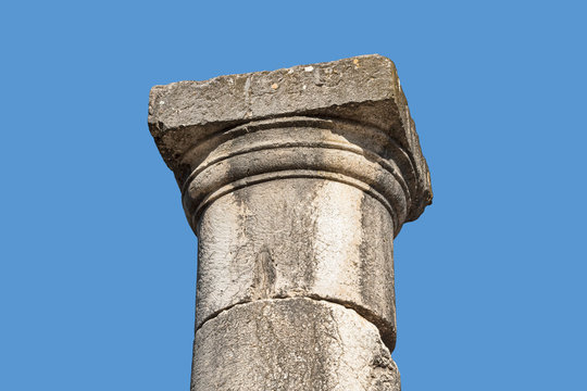 basalt stone capital in the greek doric style on top of a plain column with a sky blue background