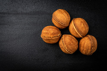 Shortbread in shape nut with caramel on black background.