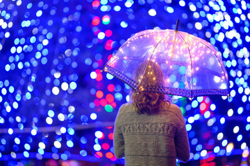 Girl in the rain with an umbrella with lights and creative lighting.Horizontal photo