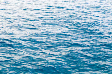 Clear water texture in blue. Background of the ocean and the sea backlit by the sun.