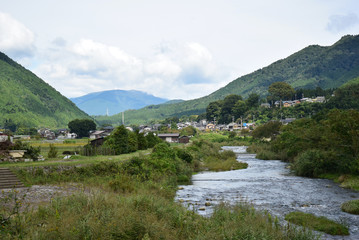 Fototapeta na wymiar A river side path, houses and mountains in Ohara town, the county side of Kyoto city in Japan.